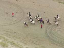 WS AERIAL ZI ZO  Horse riders riding horse on beach at west side of Romo / Ribe, Denmark Stock Footage