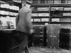 B/W 1916 Charlie Chaplin hiding from store detective behind trunks / Chaplin running offscreen Stock Footage