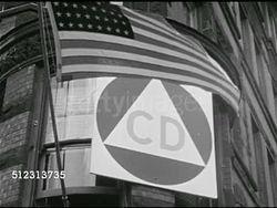1951: EMERGENCY PREPAREDNESS: DRAMATIZATION: VS Civil Defense (CD) triangle on building near American flag. Small group of city officials meeting at desk. Threats: Nuclear, biological, chemical, enemy invasion, The Red Scare, McCarthyism. Instructional Video