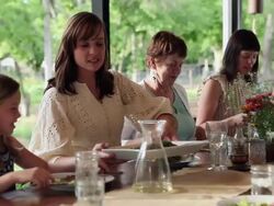 MS PAN TD men serving dishes to family seated at outdoor dinning table on porch of home Stock Footage
