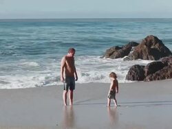 MS TS Boy runs towards man and they play with sinking their feet in  sand together then boy runs away on beach with ocean / Montezuma, Puntarenas, Costa Rica Stock Footage