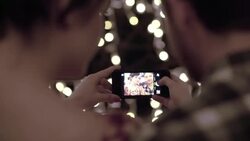 Young couple take selfies together under Christmas lights on a caf_ patio Stock Footage