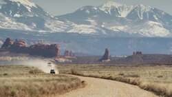 Wide shot of cars approaching on desert road / Arches National Park, Utah, United States Stock Footage