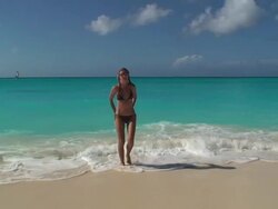 Young woman walking from ocean to the beach Stock Footage