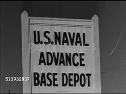 1944: UNITED STATES NAVAL DEPOT: HA WS Docked ship w/ large crane moving on pier. MS Sign,'U.S. Naval Advance Base Depot' VS Train locomotive pulling large cannon barrel outside factory. World War II, WWII, materials, weapons, recycling, home front. Instructional Video