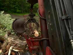 Cabin point of view of loader/slasher sawing and moving logs. Pan right to man operating the vehicle. Stock Footage