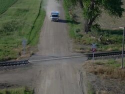 Ambulance driving across railroad tracks on a gravel road Stock Footage