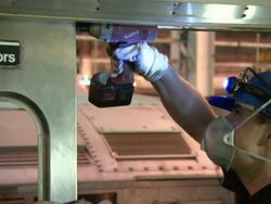 A maintenance worker uses a power drill on a train car door. Stock Footage