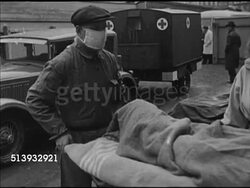 1946: RED CROSS: MEDICS: WS Two male Red Cross workers carrying injured male on stretcher. WS Males carrying wounded male on stretcher into ambulance. WS Ambulance trailer driving away. Veterans, disabled, hospital, medical attention Instructional Video