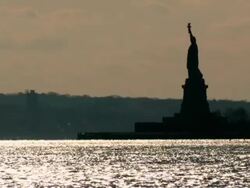 WS View of Statue of Liberty at sunset and golden sun reflecting in water/ New York City, New York, USA  Stock Footage