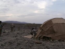 Medium Long Shot static - Children play near tent dwellings in a desert in Djibouti. / Djibouti Stock Footage