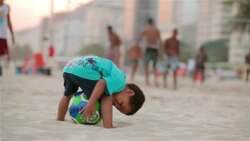 Little boy kicks up sand and pats Brazilian soccer ball on Copacabana Beach Stock Footage