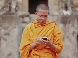 CU, PAN A Buddhist monk taps on the screen of a smartphone on an ancient temple in Angkor Wat / Siem Reap, Cambodia Stock Footage
