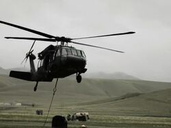 Shot from field of Black Hawk helicopter hauling off cargo. Stock Footage