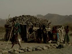Family standing next to straw and wooden hut Stock Footage