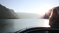 Pan as woman emerges through car roof, takes pic of sunrise Stock Footage