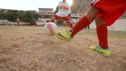 Brazilian kid in jersey kicks soccer ball during scrimmage on barren soccer field Stock Footage