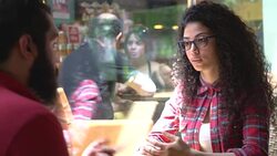 Beautiful curly haired woman with bearded young man chatting at the cafe Stock Footage