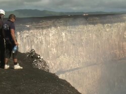 Men stand on edge of giant crater at Marum volcano, Ambrym Island, Vanuatu Stock Footage