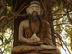 MS Statue of bearded cross legged figure in front of tree / Vientiane, Laos Stock Footage