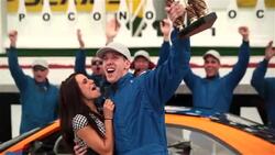Race-car driver holds up trophy, blue racing team celebrates victory Stock Footage