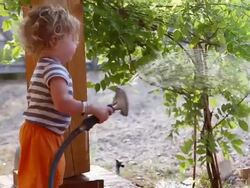 MS Shot of baby boy watering the tree with a hose / Santa Fe, New Mexico, United States  Stock Footage