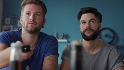 Guys sitting on couch watching tv and switching Stock Footage