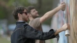 Friends cover urban wall with spray paint graffiti Stock Footage