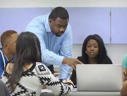 Teacher Assists Multi-Ethnic Students Using Computer Stock Footage