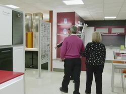 POV TS WS salesman welcoming mature couple in kitchen showroom and proceeding to walk them through the exhibit; camera follows Stock Footage
