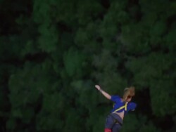 High angle slow motion shot of a person bungee jumping with their arms outstretched to the side, and giving a thumbs up sign as she come up Stock Footage