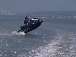 WS TS ZO SLO MO Shot of man wearing sunglasses standing up on jet ski riding in circular motion while jumping waves / New York, United States Stock Footage