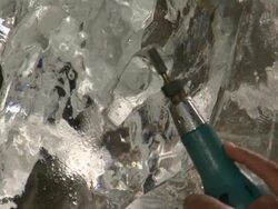 An artist uses a power tool to carve details into an ice sculpture. Stock Footage