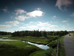 Country road with a stream and a green land beside Stock Footage