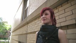 Cool young woman with red hair smoking cigarette below urban building Stock Footage