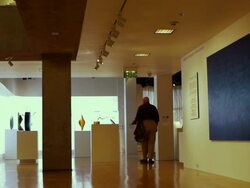 WS Visitor walking from gallery featuring modern paintings into gallery featuring contemporary art glass / Palm Springs, California, USA Stock Footage