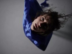 portrait of woman draped in blue silk fabric that floating around her in wind as she spins around Stock Footage