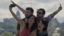 Friends pose for crazy selfie overlooking downtown Austin, Texas snd gather around smartphone to see Stock Footage