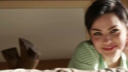 young woman lying on motel bed smiles at camera Stock Footage
