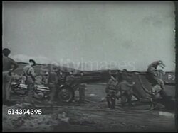 1942: ALEUTIAN ISLANDS CAMPAIGN: UNITED STATES ARMY LANDING: VS U.S. Army soldiers unloading artillery, tractors pulling cannons, anti-air defense gun rotating on crowded beach of Adak island. VS Soldiers w/ gear unloading, walking. WWII, Alaska Instructional Video