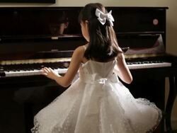 TU Rear view girl in white dress playing piano turns and smile Stock Footage