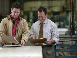 Factory worker and supervisor looking at paperwork, shake hands and leave Stock Footage