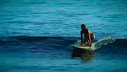A cute surfer girl catches an ocean wave and rides it with grace and poise, showcasing femininity but with an edge of athleticism and grace. Stock Footage