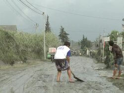 Men scrape volcanic ash mud off road after eruption of Merapi volcano; Indonesia. 7 November 2010 / AUDIO Stock Footage
