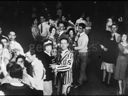 1920s: MARATHON DANCING: Sign for 'Marathon Dance Contest...' Couple entering dance hall door, VS Couples dancing on dance floor, MS Woman on cot having legs messaged by male hands, male shaving while slow dancing w/ partner.  (No Charleston, Shag) Instructional Video