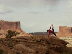 Wide shot of woman doing yoga on mountain / Moab, Utah, United States Stock Footage