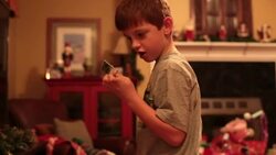 Boy looks at parts and pieces of his train Christmas morning as his train derails Stock Footage