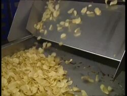 MS Potato chips falling down chute onto conveyor belt Stock Footage