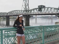 MS Shot of young female jogger relaxes on railing at city waterfront after her jog and drinking water in bottle / Portland, Oregon, United States  Stock Footage
