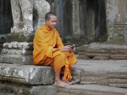 WS, PAN A Buddhist monk taps on the screen of a smartphone on the steps of an ancient temple in Angkor Wat / Siem Reap, Cambodia Stock Footage